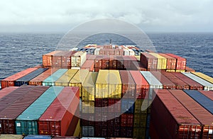 Large container ship, fully loaded with colorful containers sailing through the Pacific Ocean