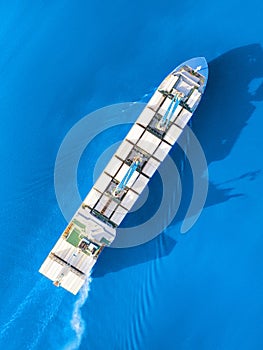 Large container ship sailing blue sea. Top aerial view