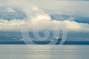 Large container ship sailing at sea in overcast morning close to the Rijeka town shoreline in Croatia