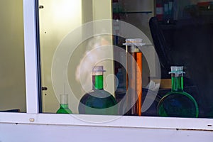 Large containers with multi-colored chemicals behind glass