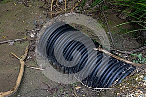 A large, corrugated black pipe pokes out from the ground