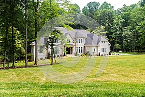 Large country home with large green lawn in front yard. And woods in the backyard