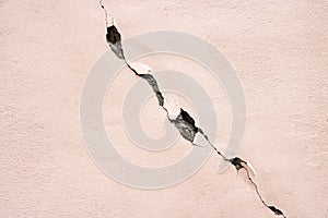 A large crack on the pink wall