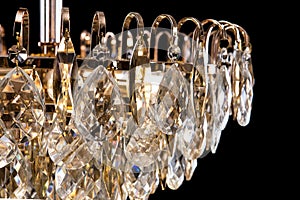 Large crystal chandelier detail isolated on black background.