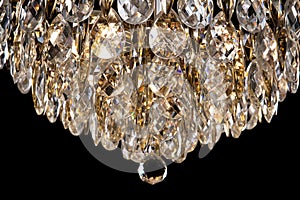 Large crystal chandelier detail isolated on black background.