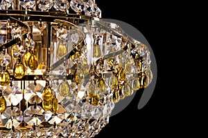 Large crystal chandelier detail isolated on black background.