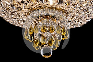 Large crystal chandelier detail isolated on black background.