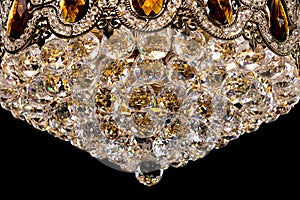 Large crystal chandelier detail isolated on black background.