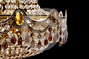 Large crystal chandelier detail isolated on black background.