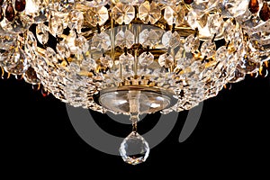 Large crystal chandelier detail isolated on black background.