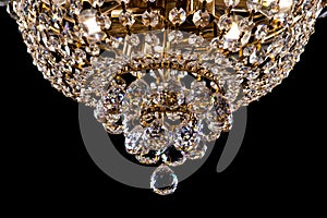 Large crystal chandelier detail isolated on black background.