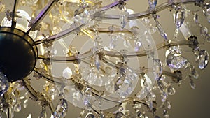 large crystal chandelier glowing in the ceiling in the restaurant, easy twisting on the axis. close-up.
