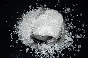 Large crystal of salt on black reflective surface; selective focus; natural edible salt