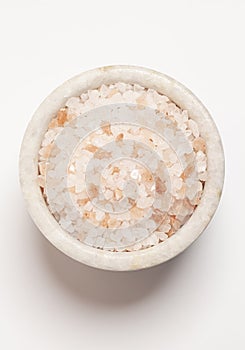 Large crystals pink Himalayan salt in a marble box isolated on white background,top view.
