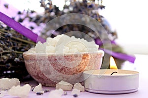 Large crystals of sea salt and lavender flowers, lit candle.