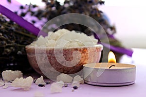 Large crystals of sea salt and lavender flowers, lit candle.