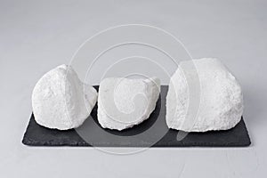 Large crystals of sodium chloride- food salt on a black stone board. Food flavor enhancer. Organic NaCl natural minerals