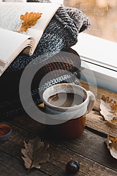 Large Cup of cappuccino on vintage brown background. Autumn, fall leaves, hot steaming cup of coffee and a warm scarf on wooden ta