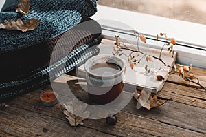 Large Cup of cappuccino on vintage brown background. Autumn, fall leaves, hot steaming cup of coffee and a warm scarf on wooden ta