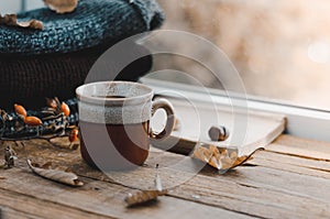 Large Cup of cappuccino on vintage brown background. Autumn, fall leaves, hot steaming cup of coffee and a warm scarf on wooden ta