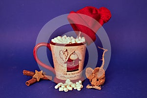 A large cup of coffee with a picture of Santa Claus on it and with marshmallows inside it stands on a blue background