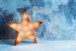 Large decorative retro star with lots of burning lights on grunge concrete background. Beautiful decor, modern design