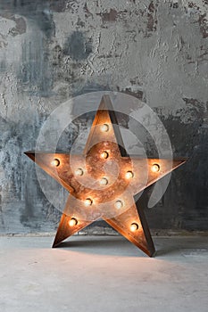 Large decorative retro star with lots of burning lights on grunge concrete background. Beautiful decor, modern design