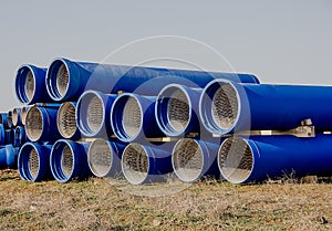 Large diameter blue concrete pipes lie in the field