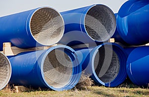 Large diameter blue concrete pipes lie in the field