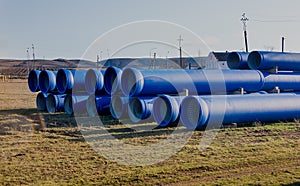 Large diameter blue concrete pipes lie in the field