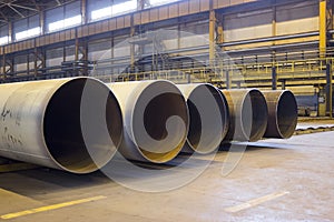 Large diameter pipes are stacked in an industrial factory shop