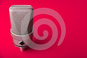 Large diaphragm condenser studio microphone. On a red background.