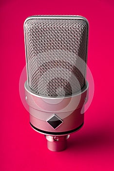 Large diaphragm condenser studio microphone. On a red background.