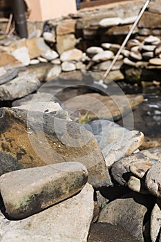 Large dirty stones in the background of the pool. Construction and cleaning of an ornamental pond in the garden. landscape design