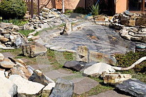 Large dirty stones in the background of the pool. Construction and cleaning of an ornamental pond in the garden. landscape design
