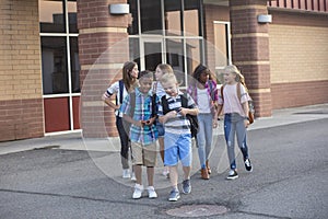 Large, diverse group of kids leaving school at the end of the day. School friends walking together and talking together on their w