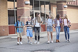 Large, diverse group of kids leaving school at the end of the day. School friends walking together and talking together on their w