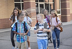 Large, diverse group of kids leaving school at the end of the day. School friends walking together and talking together on their w