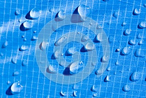 Large drops of water on a blue textile with a waterproof effect. Water-repellent impregnation.