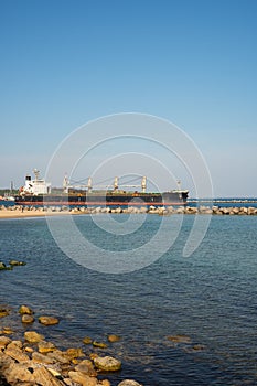 A large dry cargo ship leaves the port past the breakwater.