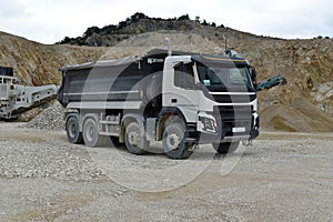 A large dump truck is parked in a quarry