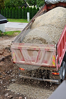 Large dump truck unloads rubble or gravel at construction site.