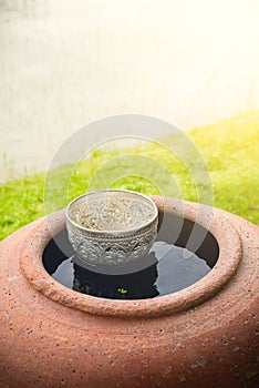 Large earthenware water container (Jar) and silver dipper.