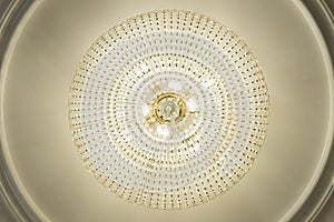 Large electric chandelier made of glass beads on a white decorative ceiling decorated with stucco molding