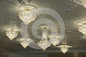 Large electric chandelier made of glass beads on a white decorative ceiling decorated with stucco molding