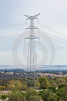 Large electrical tower linked by electrical cables in the center of a field