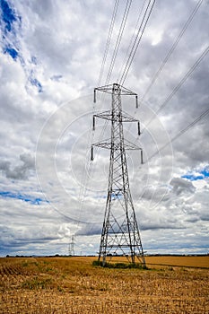Large electricity pylon with pylons in the distance in a field of corn stubble