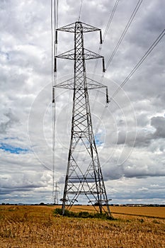 Large electricity pylon with pylons in the distance in a field of corn stubble