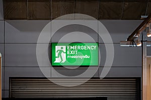 Large Emergency exit sign green light box is placed on the wall of exhibition hall. Thai Letter is Thai Language on the green