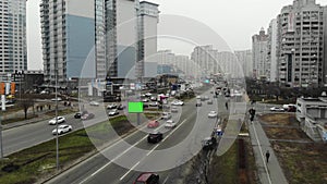 Large empty billboard with a green screen for advertising on the modern building near speed highway, urban interchange